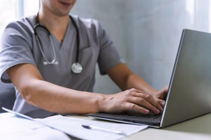 side-view-doctor-with-stethoscope-working-laptop_23-2148735407